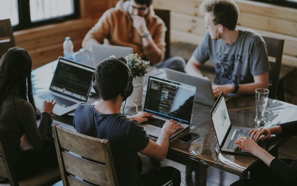 Gruppe arbeitet gemeinsam an einem Laptop: Teamkultur hilft, Fachkräfte binden zu können