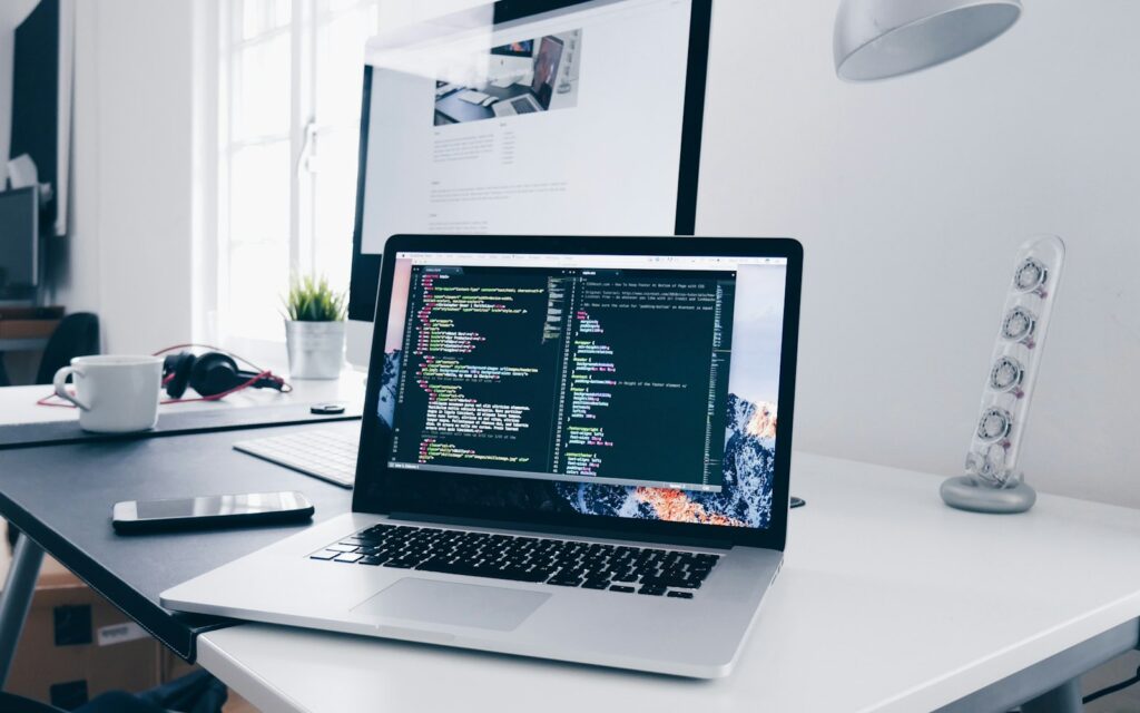 Laptop mit Programmcode als Symbol für Inhouse-Entwicklung im Unternehmen