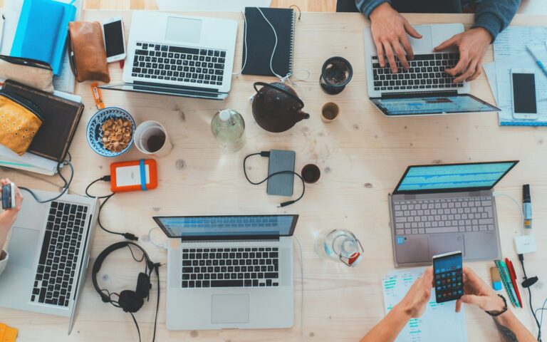 Team mit mehreren Laptops arbeitet gemeinsam an einem Tisch an der Inhouse-Entwicklung