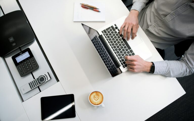 Person arbeitet am Laptop auf einem Holztisch, Symbolbild zu Copilot im Unternehmen