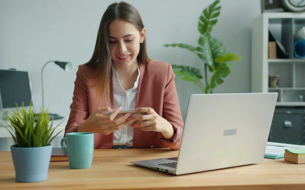 Mitarbeiterin arbeitet am Schreibtisch mit Laptop, Symbolbild zu Diensthandy private Nutzung