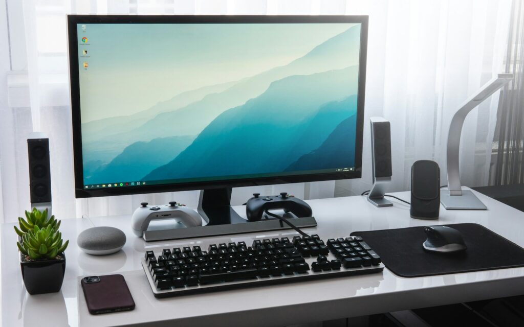 Monitor und Tastatur auf einem weißen Schreibtisch, Symbolbild zu Digitale Wirtschaftsgüter Abschreibung