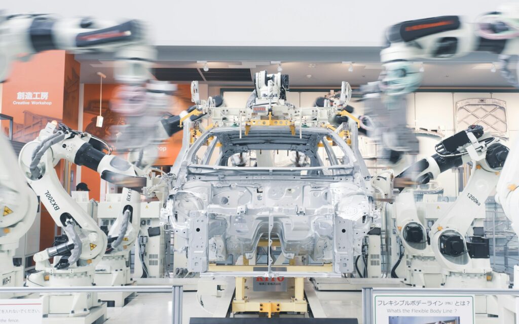 Roboterarme montieren ein Autochassis in der Fertigung, Symbolbild zu digitaler Zwilling