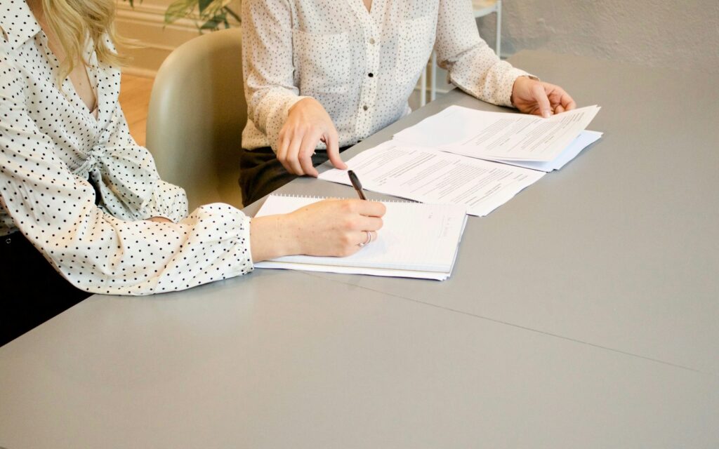 Zwei Frauen prüfen und unterschreiben Dokumente, Symbolbild zu E-Rechnung empfangen