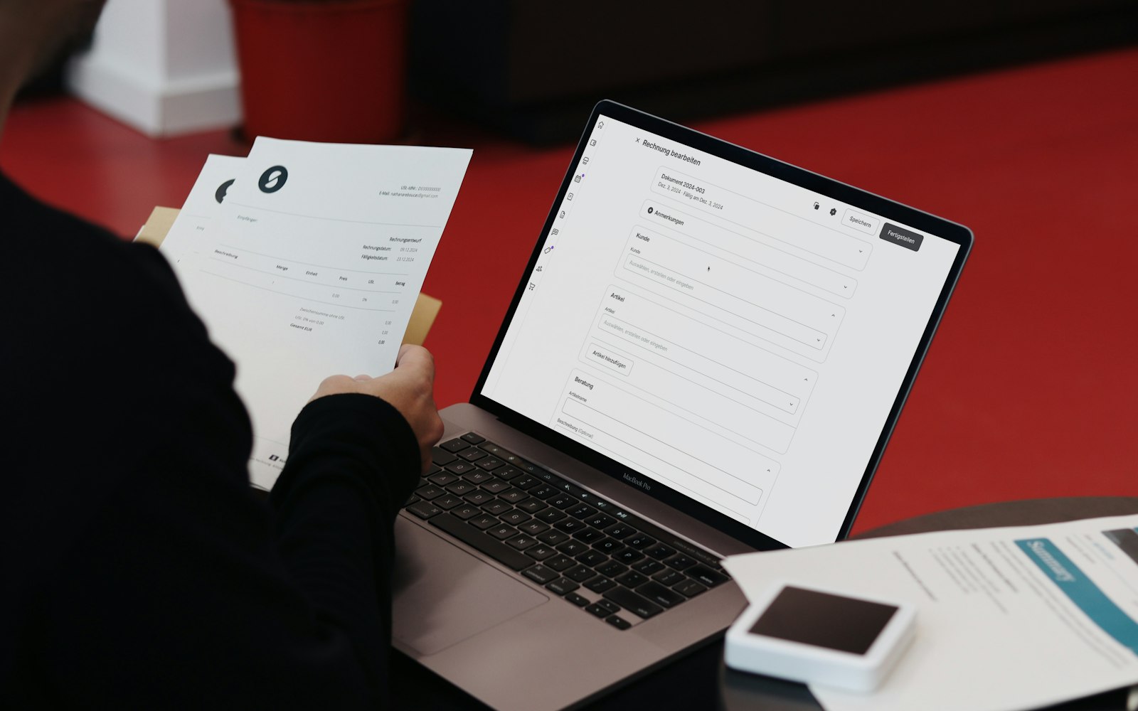 Person arbeitet mit Laptop und Rechnungen am Schreibtisch, Symbolbild zu E-Rechnung Pflicht 2027