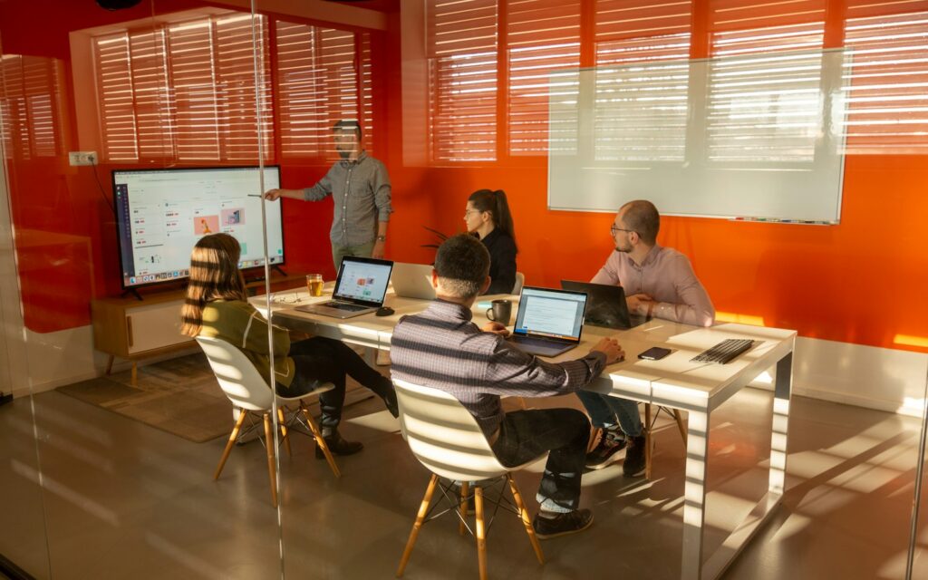 Projektteam sitzt mit Laptops um einen Tisch, Symbolbild zu Führen ohne Weisungsbefugnis