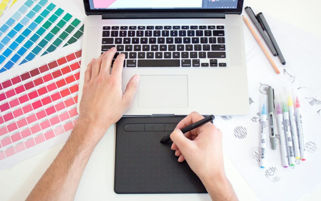 Designerin arbeitet mit Zeichentablett und Laptop, Symbolbild zu KI-Bilder kommerziell nutzen