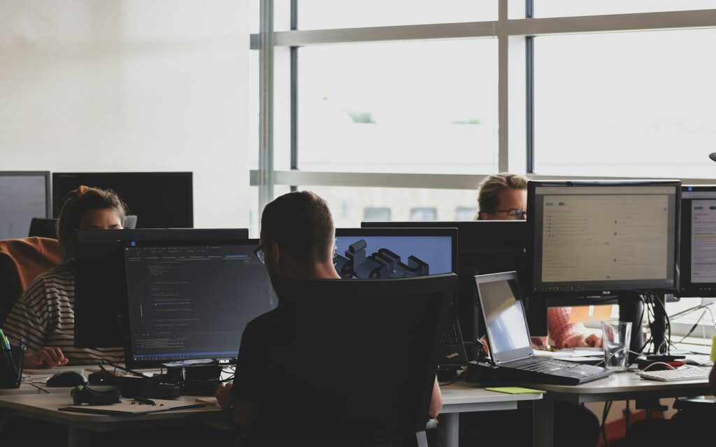 Team arbeitet gemeinsam an Computern im Büro an Projekten zu KI im Mittelstand