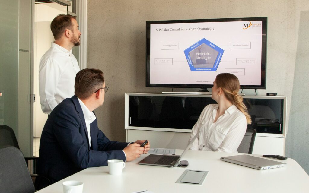 Team verfolgt eine Präsentation im Besprechungsraum, Symbolbild zu Revenue Operations