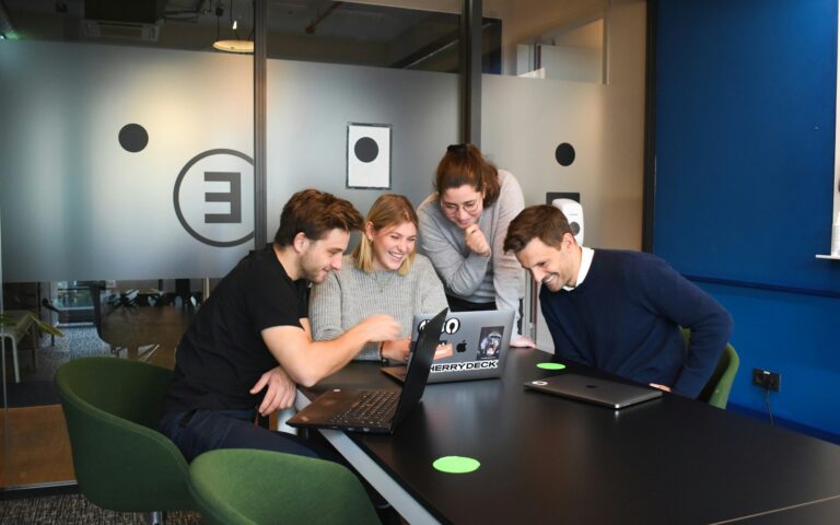 Team arbeitet an Laptops im Büro und testet die Vier-Tage-Woche im Arbeitsalltag